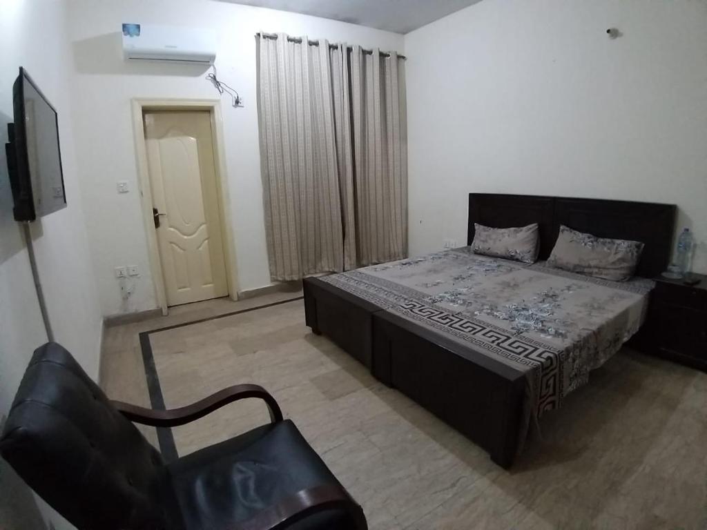 a bedroom with a bed and a chair in it at Guest House & Apartments Johar Town near Emporium & Expo in Lahore