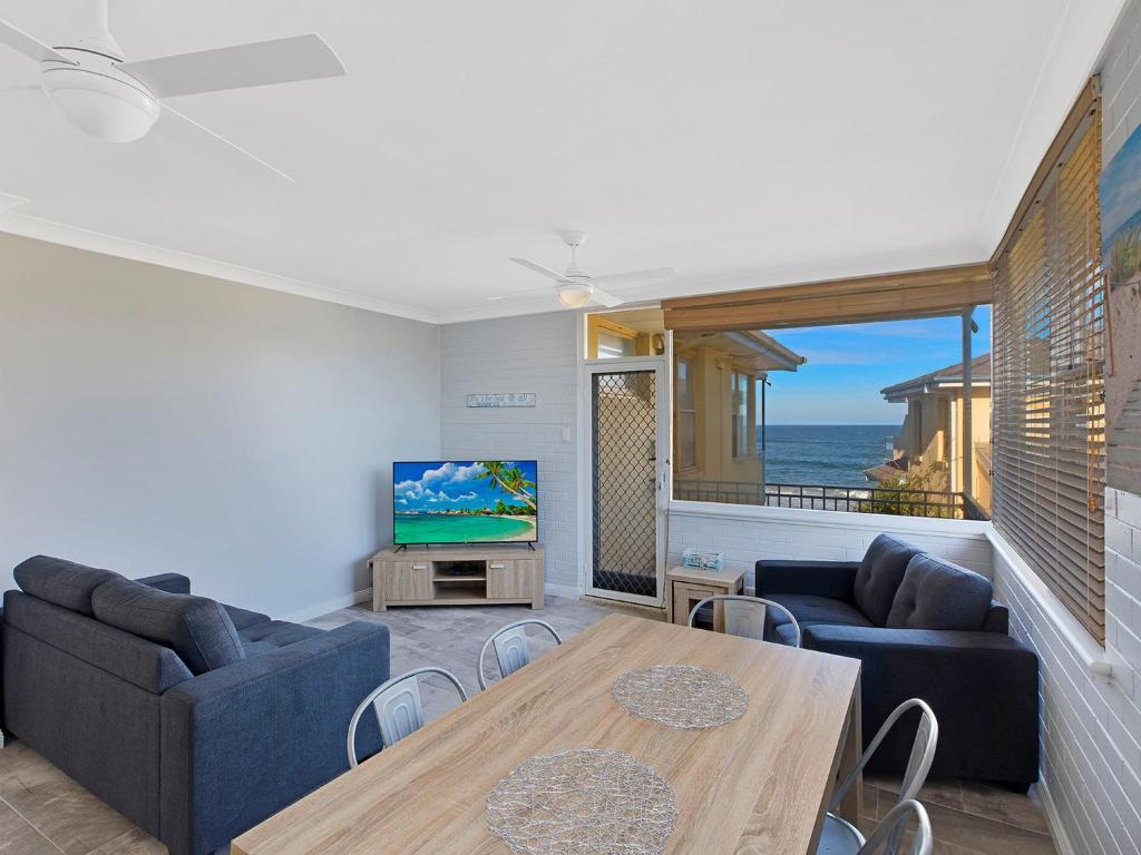 a living room with a table and a television at Golden Sands Apartment 10 in The Entrance