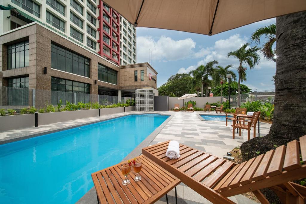 a swimming pool with a table and chairs and a building at Travelodge Ipoh in Ipoh