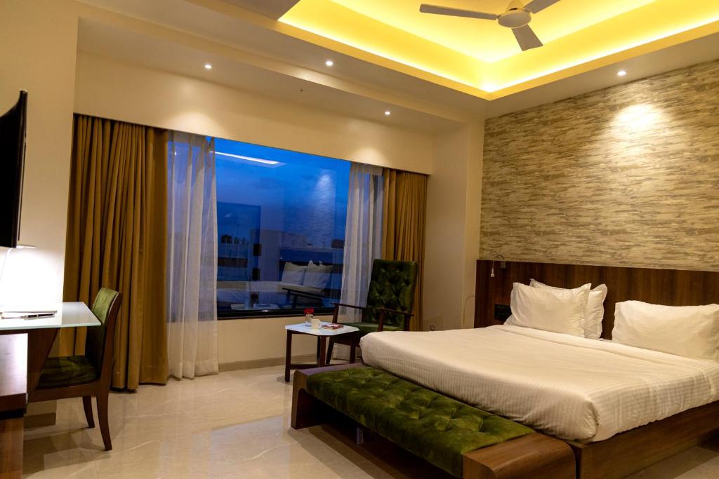 Un dormitorio con una cama grande y una ventana en Hotel Pratham, en Solapur