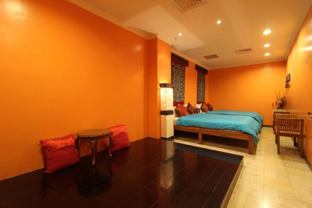 a bedroom with orange walls and a bed and a table at Golden Ocean Azure Hotel in Kenting