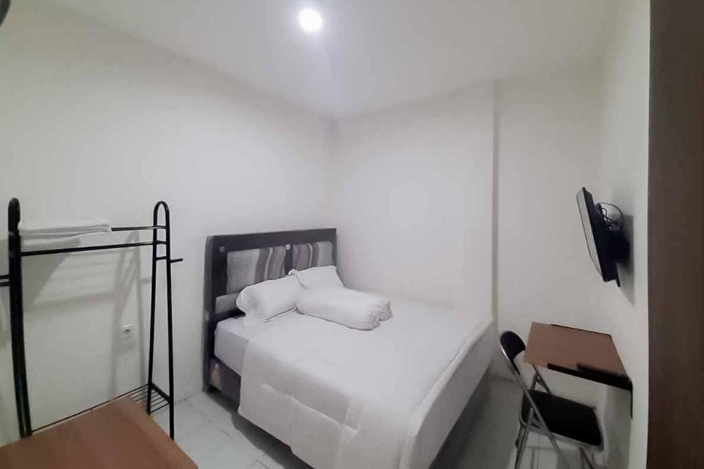 a white bedroom with a bed and a chair at RedDoorz near Alun Alun Kota Serang in Gedeg
