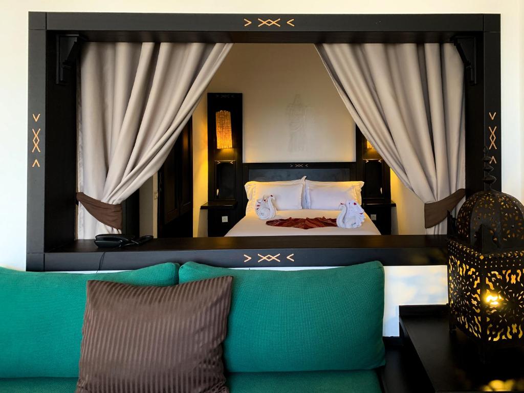 een slaapkamer met een bed met gordijnen en een bank bij Borjs Hotel Suites & Spa in Agadir