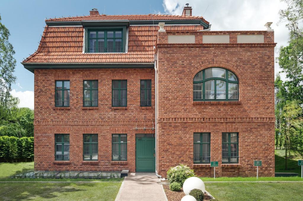 a red brick house with a green door at Pensjonat Victoria by OneApartments in Sopot