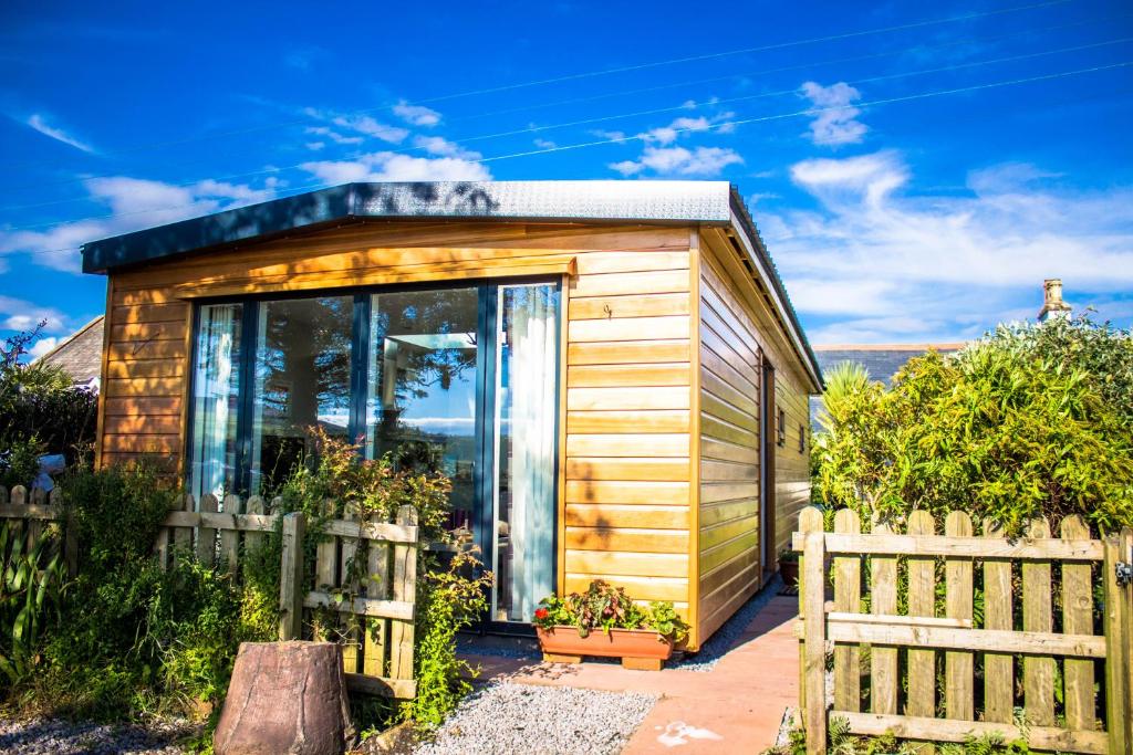 Sunset Retreat Lodge with Hot Tub في Carsethorn: منزل خشبي صغير مع سور خشبي