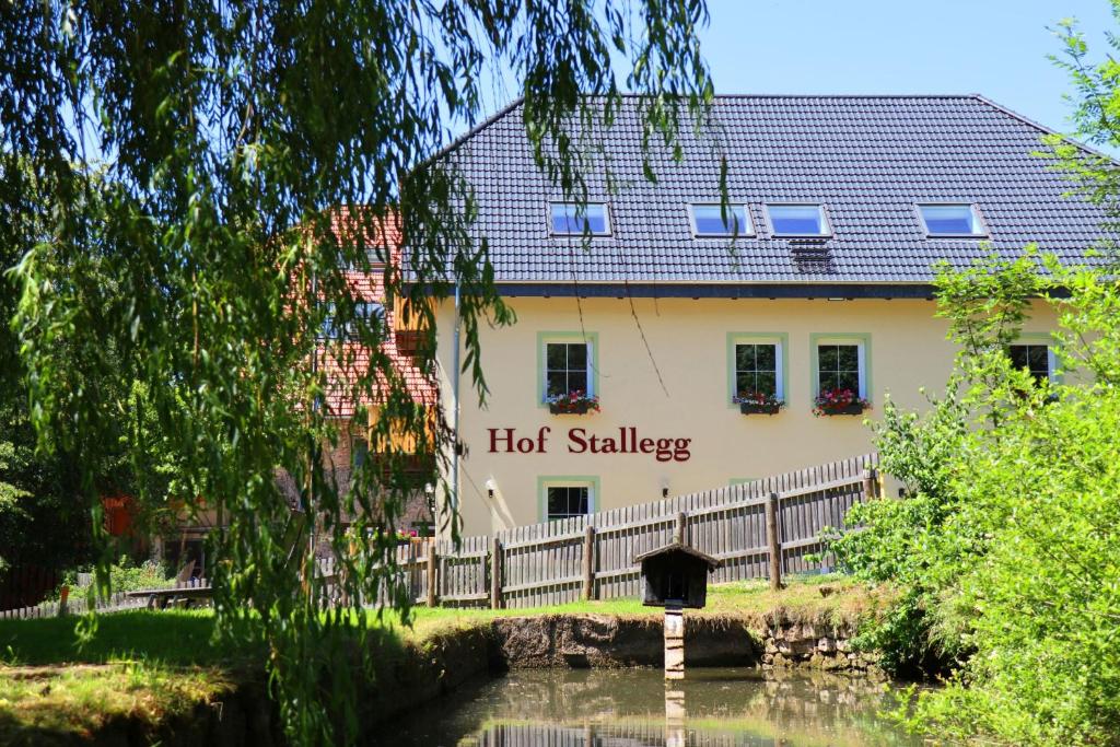 a building with a hot sausage sign next to a river at Hof Stallegg in Löffingen