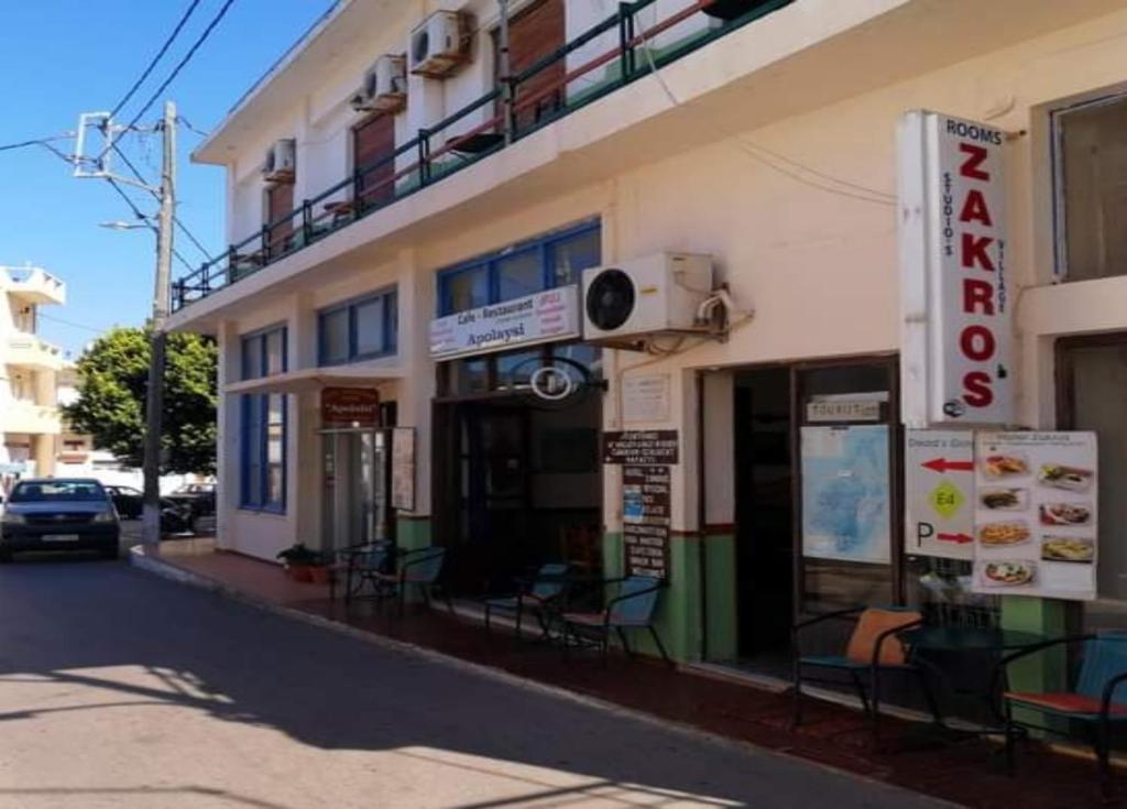 a building on a street with chairs in front of it at Hotel zakros rooms-restaurant in Zákros