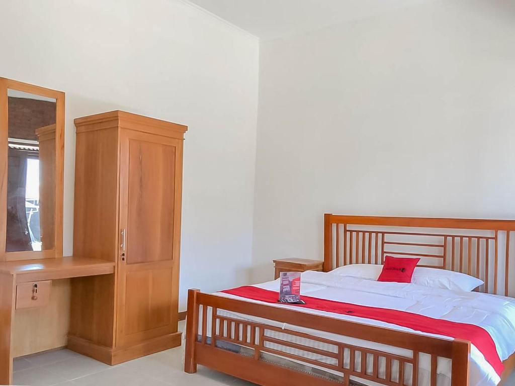 a bedroom with a bed with a red pillow and a cabinet at RedDoorz Resort near Darajat Garut in Garut