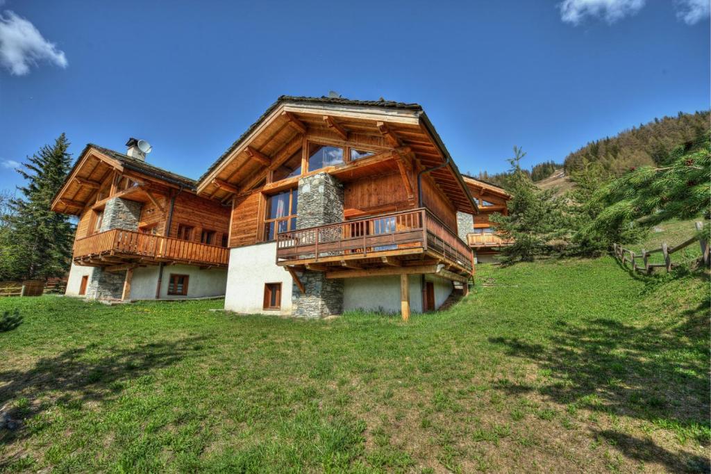 Cette grande maison en bois dispose d'un balcon sur une colline. dans l'établissement Chalet ALPACA Peisey-Vallandry - Domaine Paradiski, à Peisey-Nancroix