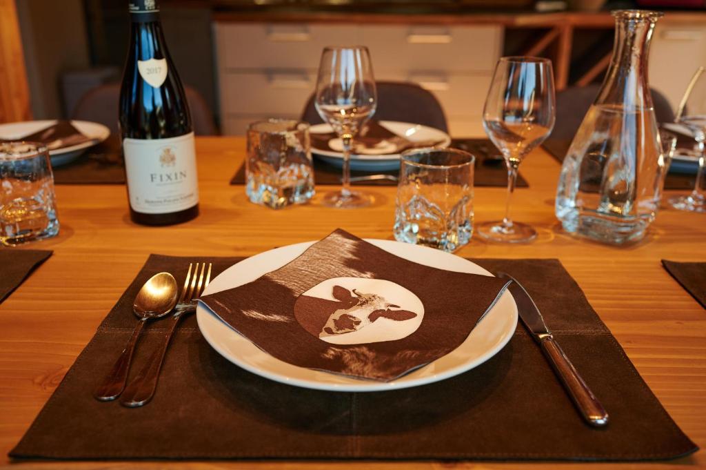 a wooden table with a plate and a bottle of wine at Chalet ALPACA Peisey-Vallandry - Domaine Paradiski in Peisey-Nancroix