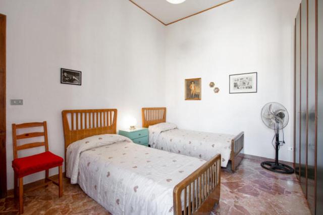 1 Schlafzimmer mit 2 Betten, einem Ventilator und einem Stuhl in der Unterkunft Casa Vacanze Casa Ida in Cava deʼ Tirreni