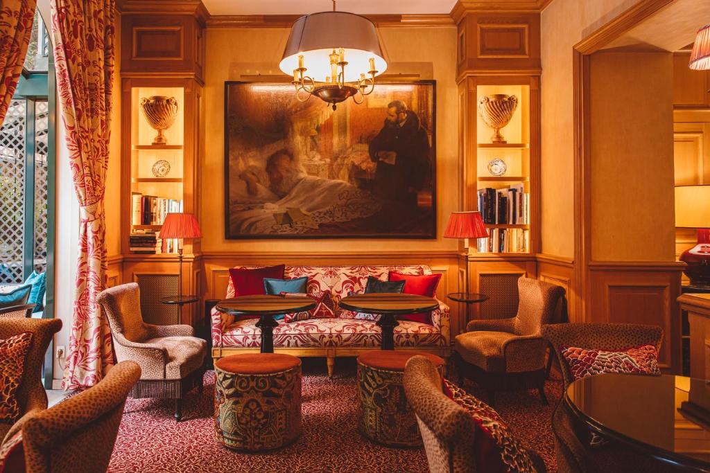 a living room with a couch and tables and chairs at Hôtel de l&#39;Abbaye in Paris