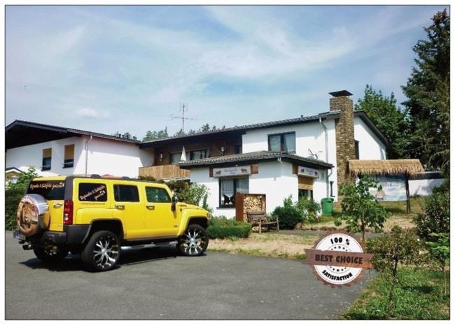 un camión amarillo estacionado frente a una casa en zu Jeddelohs Lodge Hotel, en Gladenbach