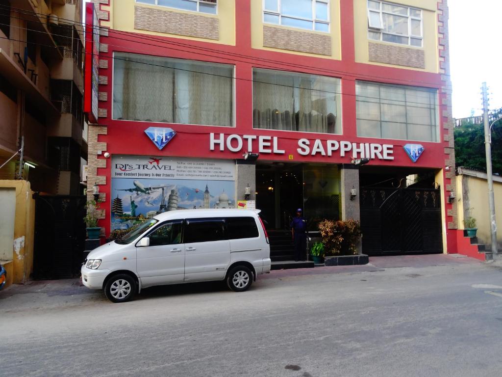 una furgoneta blanca estacionada frente a un hotel zafiro en Hotel Sapphire, en Dar es Salaam