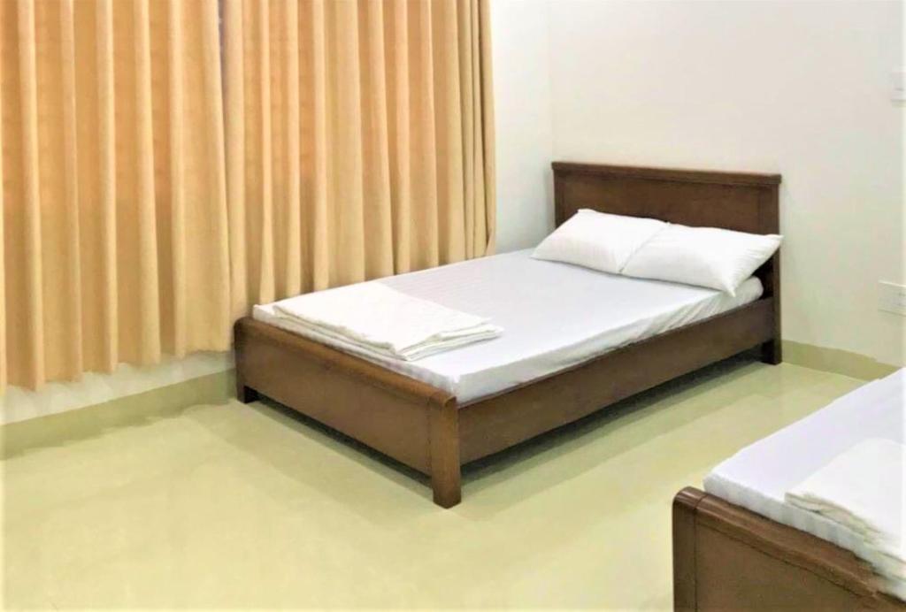 a bedroom with a bed with white sheets and curtains at Dung Khanh Motel in Dĩ An