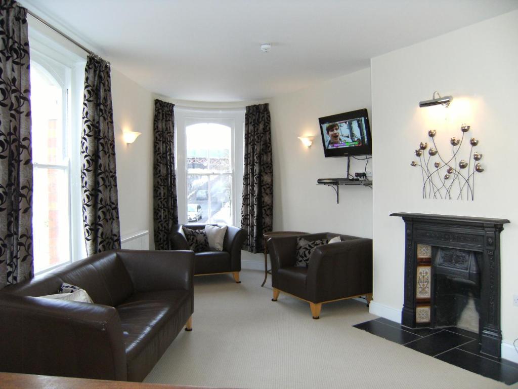 a living room with leather furniture and a fireplace at Cotswolds Valleys Accommodation - Bell Apartments - Exclusive use large two bedroom family holiday apartment in Stroud