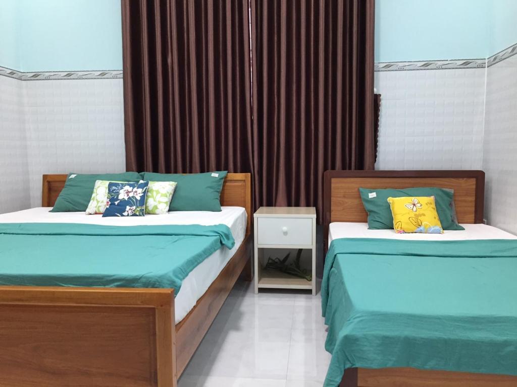 1 dormitorio con 2 camas y sábanas azules en HÒANG HÔN HOMESTAY, en Ben Tre
