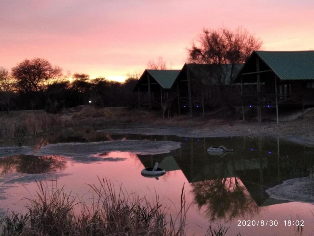 a reflection of two barns in a pond at sunset at Hanlin Lodge in Modimolle