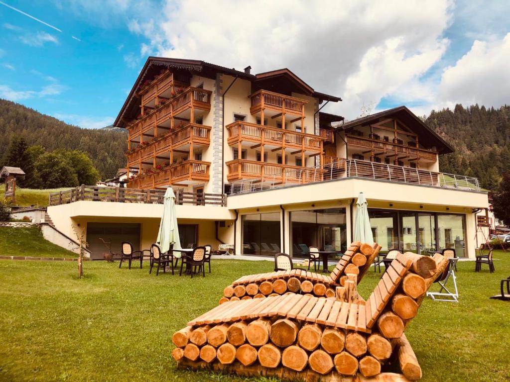 a large log house with a bench in front of it at Wellness Hotel Dolomia in Soraga