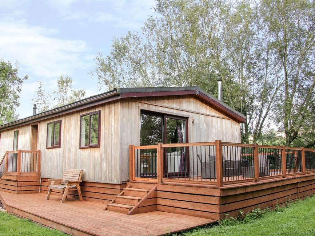 une grande cabine en bois avec une grande terrasse dans l'établissement Alder River Lodge Clun Valley Luxury Hot Tub Break, à Craven Arms