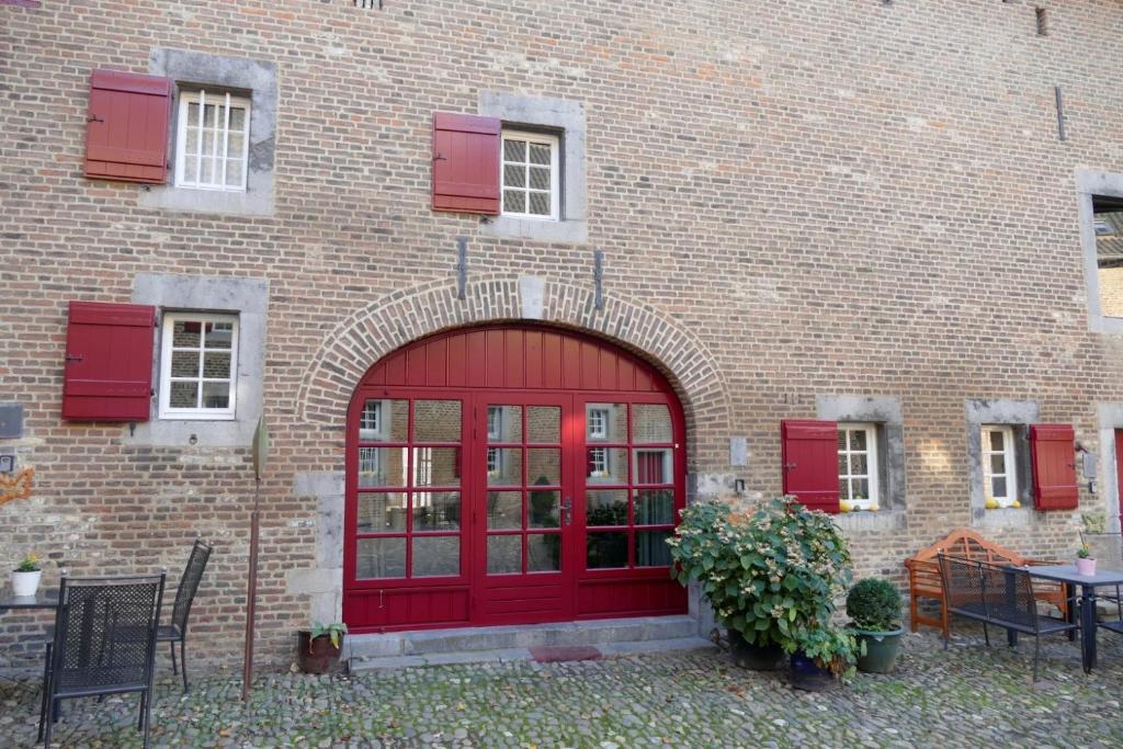 een rode deur op een bakstenen gebouw met rode luiken bij Meschermolen 3 in Withuis