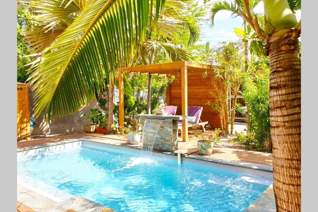 a swimming pool with a gazebo and a palm tree at VILLA KADAL, perle rare à 50m du lagon… in La Saline les Bains