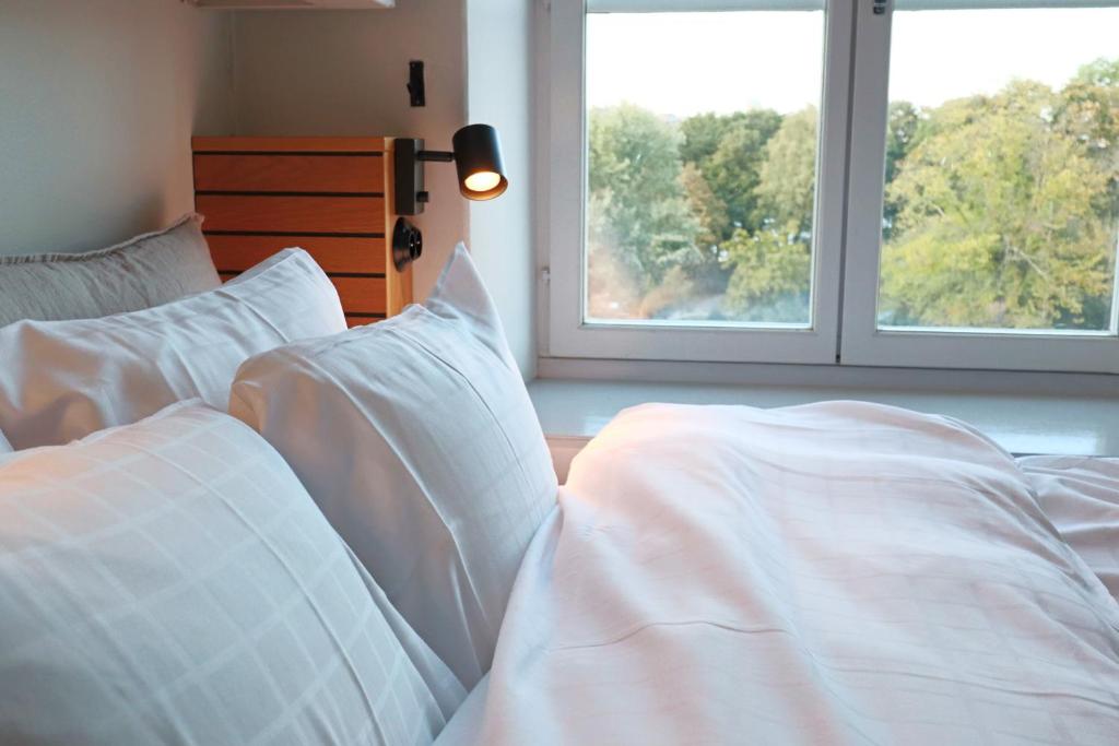 a bedroom with two beds with white sheets and two windows at Långholmen Hotell in Stockholm