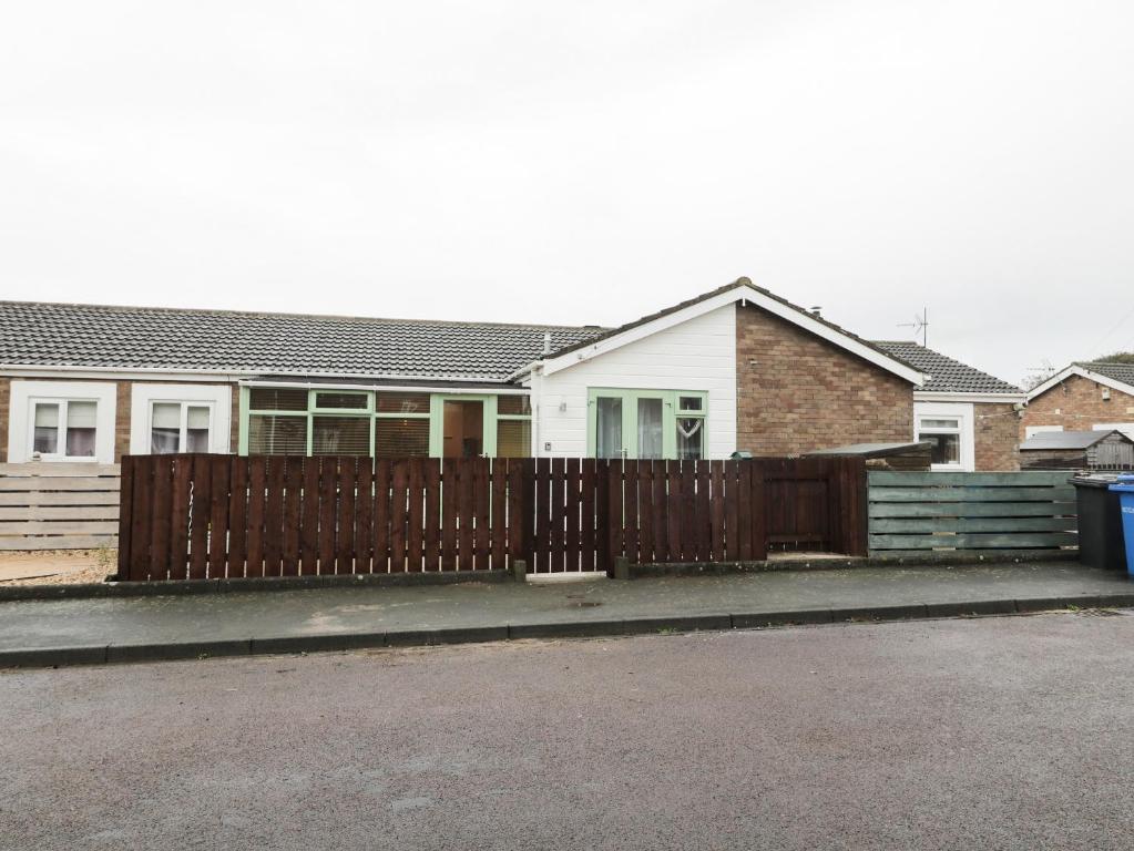a wooden fence in front of a house at Swale Cottage in Chathill