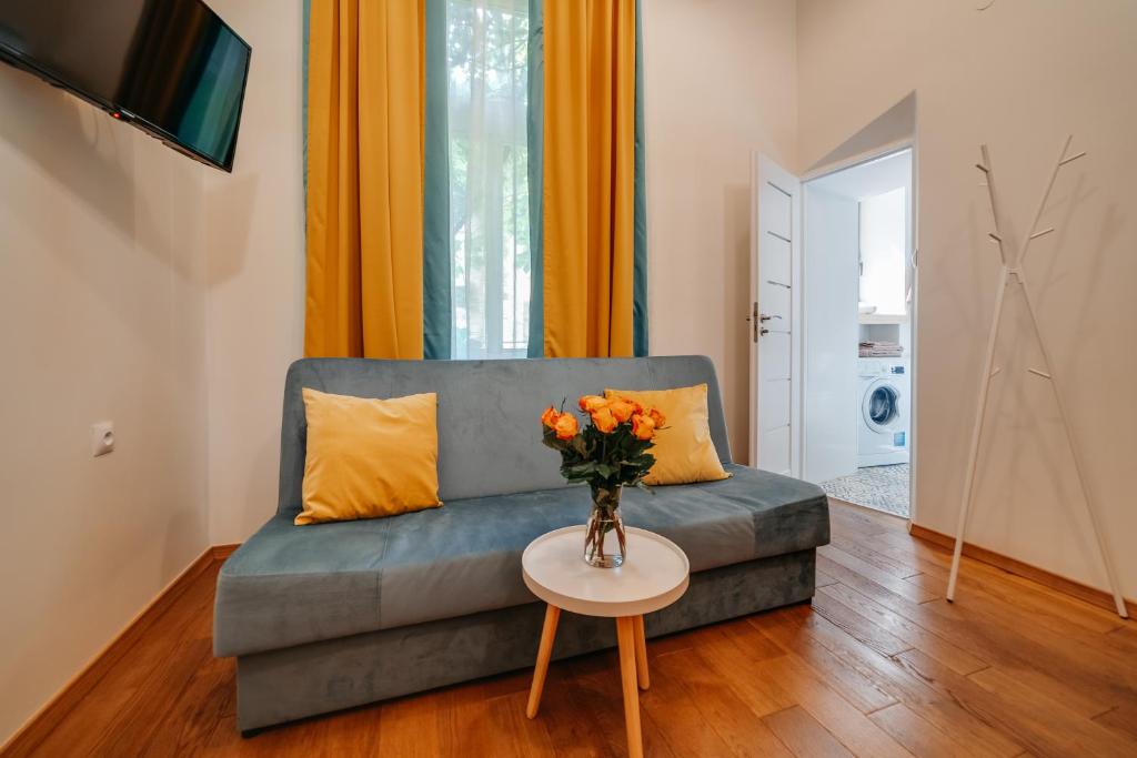 a living room with a couch and a table with flowers at ALPARI apartments in Krakow