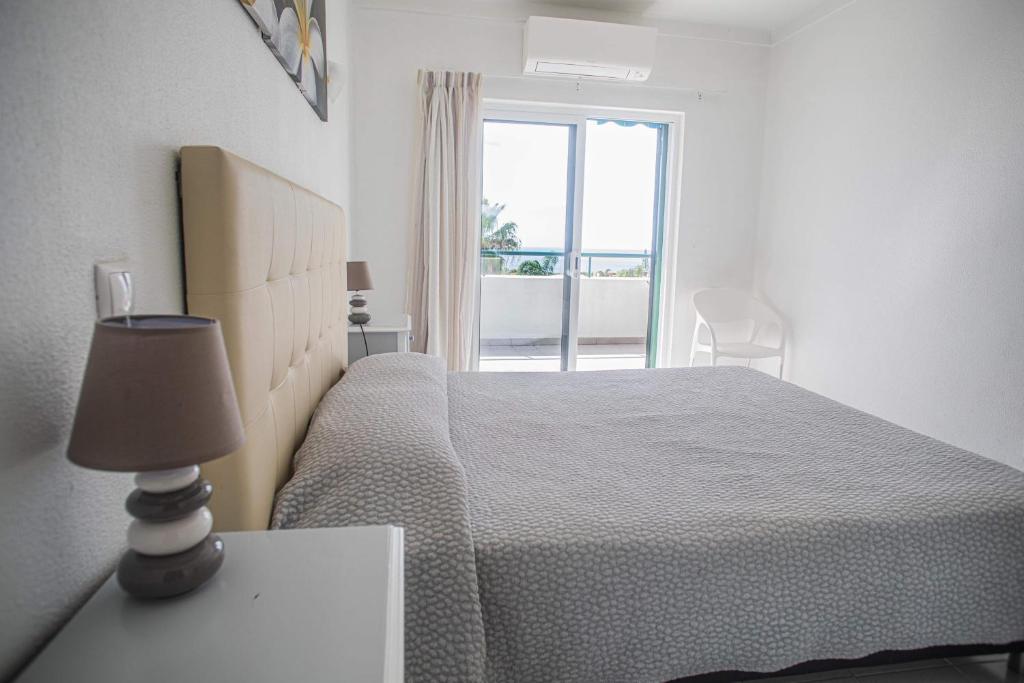 a white bedroom with a bed and a window at Debimar Apartamentos in Albufeira