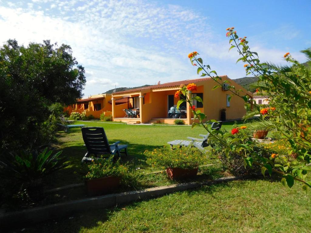 uma casa com um quintal com um banco e flores em Residence La Pineta em Budoni