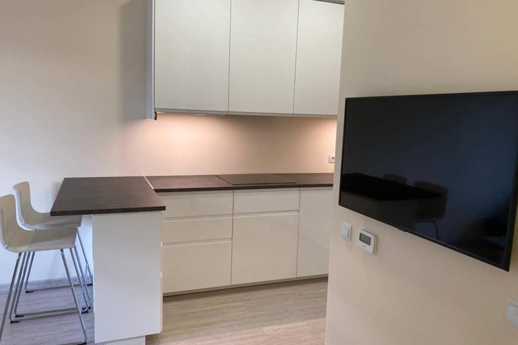 a kitchen with white cabinets and a large flat screen tv at Lazdyneliu Apartamentai in Vilnius