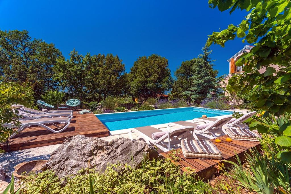 a swimming pool with a deck and chairs next to it at Villa Tajina Kuca in Žeževica