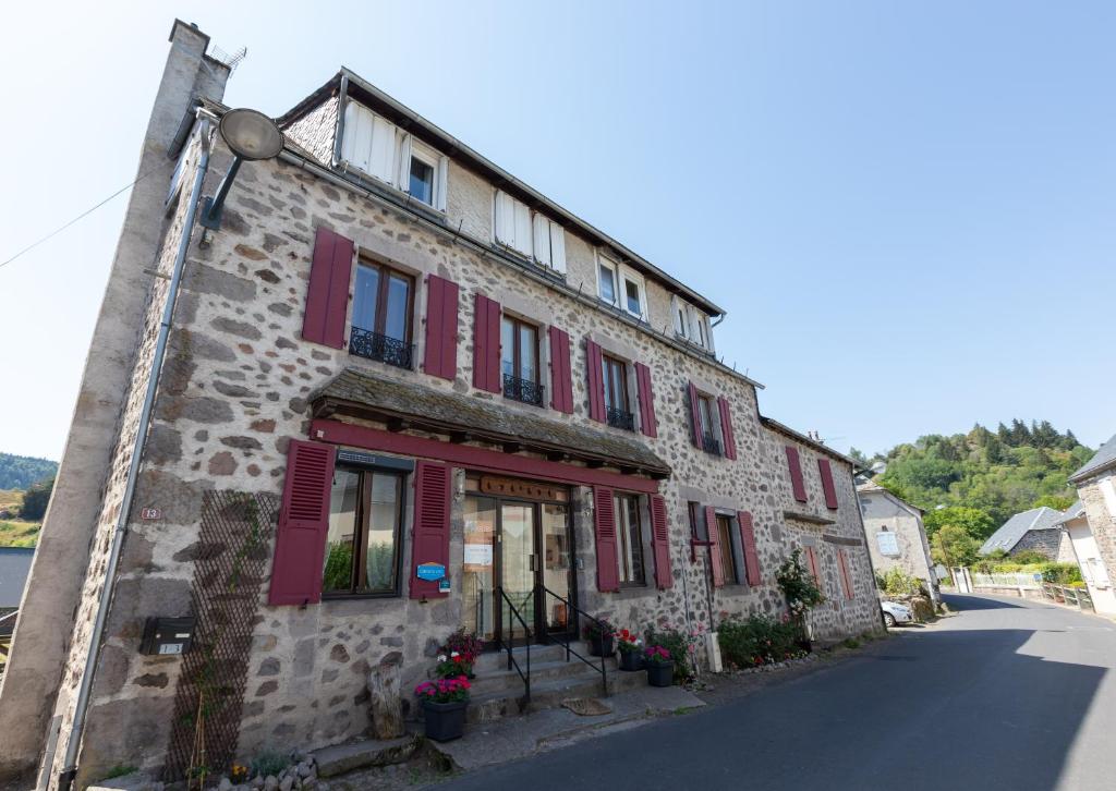 Albepierre-BredonsにあるLa Belle Arverneの通り上の赤い襖の古い石造りの建物