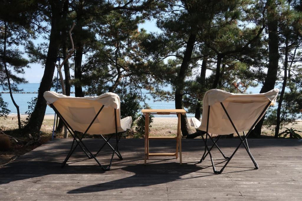 two chairs and a table in front of the beach at 奈多みどり荘 Nada Beach House in Kitsuki