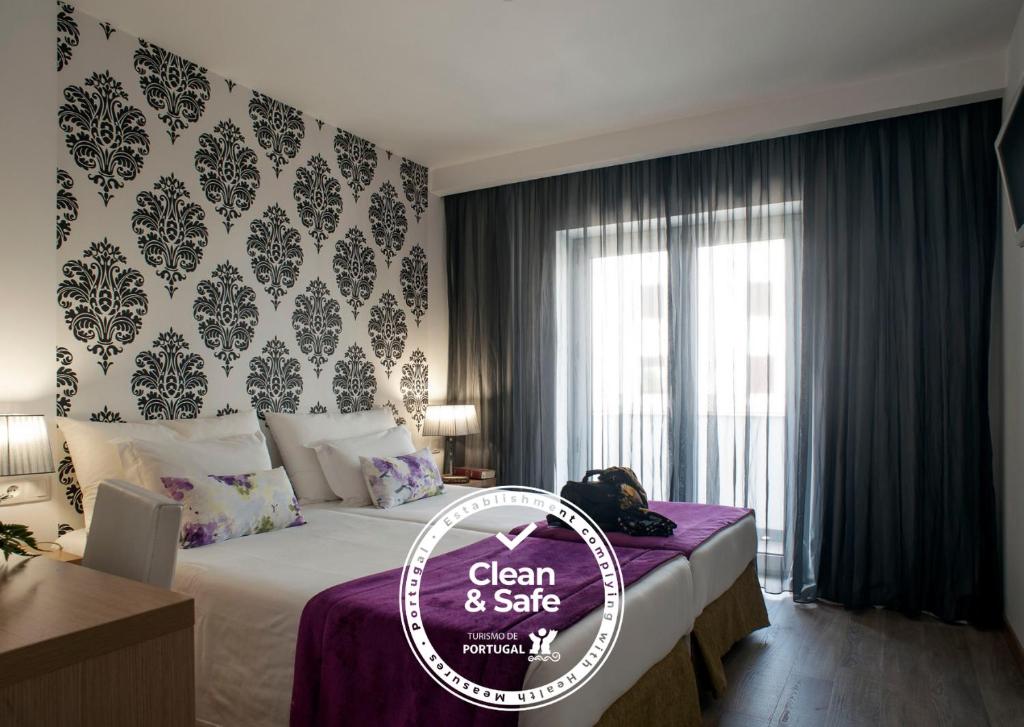 a hotel room with a clean and safe sign on a bed at Hotel Genesis in Fátima