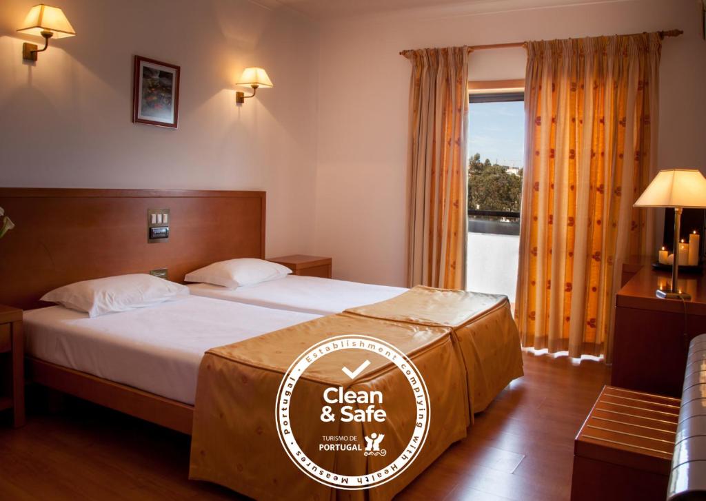 a hotel room with a bed with a sign for clean and safe at Hotel Santa Mafalda in Fátima