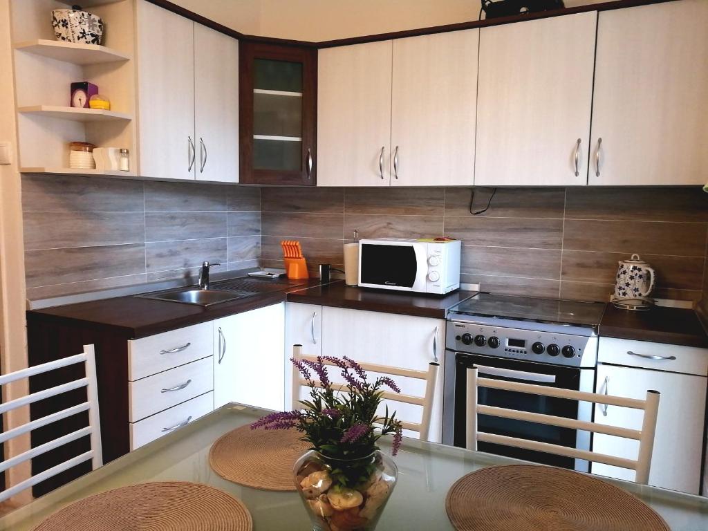 a kitchen with white cabinets and a table with chairs at Apartmani Paula in Rab