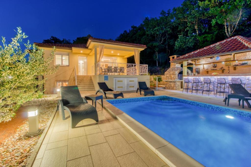 a swimming pool with chairs and a house at Villa Sole in Omišalj