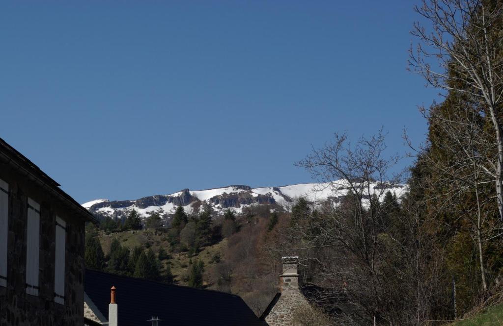 Une montagne enneigée au loin derrière une maison dans l&#39;établissement La Belle Arverne, à Albepierre-Bredons