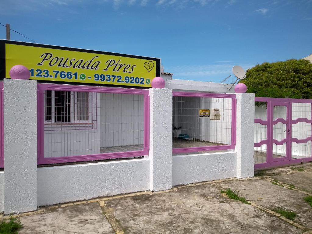 un edificio rosa y blanco con un cartel en él en Pousada Pires, en Tramandaí