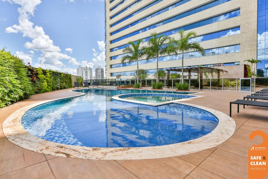 a swimming pool in front of a tall building at Transamerica Collection Goiânia in Goiânia