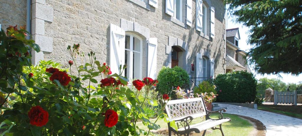 un banco frente a una casa con flores rojas en Le Chatellier, en Cancale