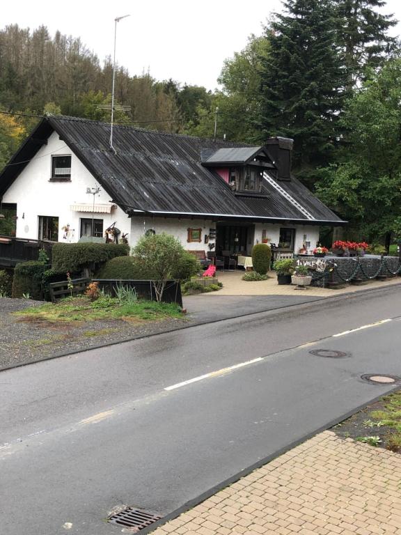 a white house with a black roof next to a road at Ferienwohnung Wolf in Reichshof 