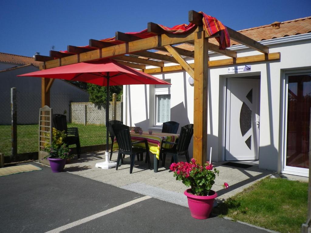 patio con tavolo e ombrellone rosso di Résidence Les Océanes a Les Sables-dʼOlonne