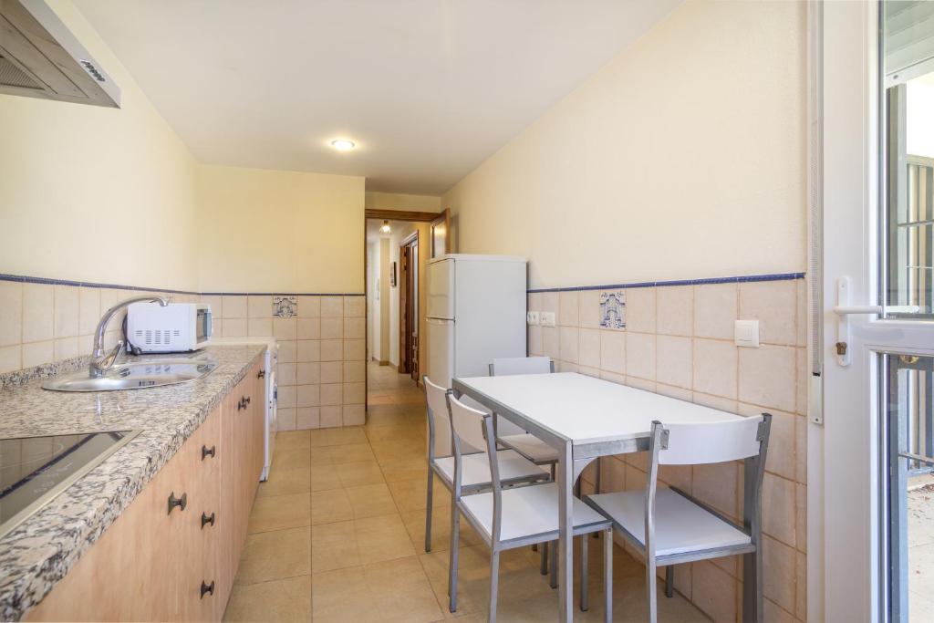 a kitchen with a table and chairs and a refrigerator at Zahara Sol Villas y Apartamentos by QHotels in Zahara de los Atunes