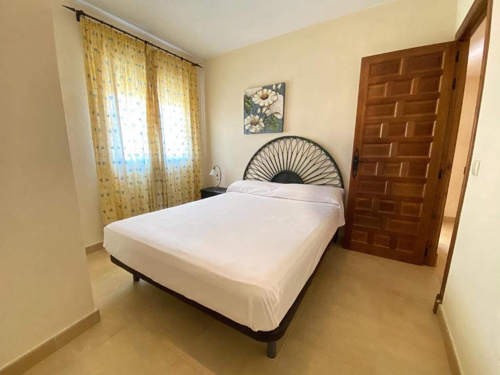 a bedroom with a large bed and a wooden door at Zahara Sol Villas y Apartamentos by QHotels in Zahara de los Atunes