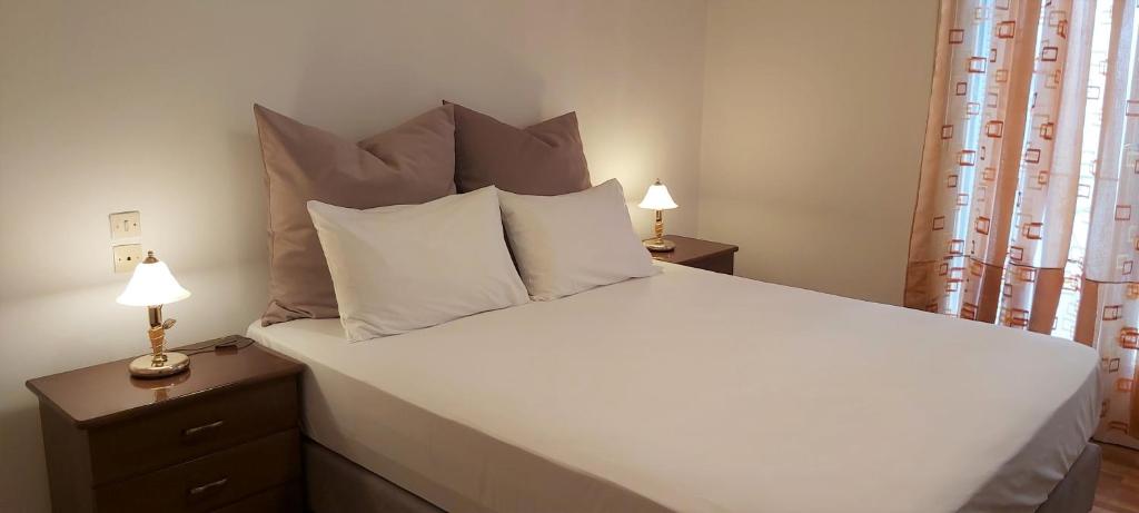 a bedroom with a large white bed with two lamps at The comfy flat in Athens