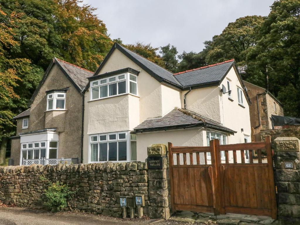 a house with a wooden gate and a stone fence at Coppice Hollow in Buxton