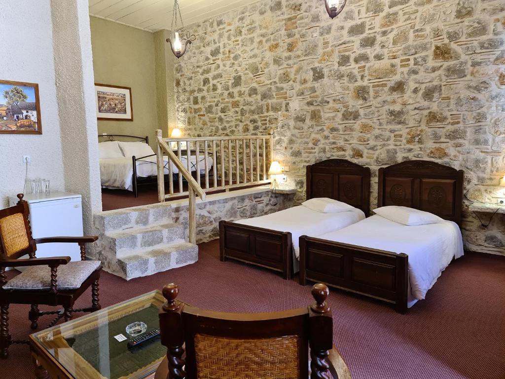a bedroom with two beds and a stone wall at Pension Maria in Arachova